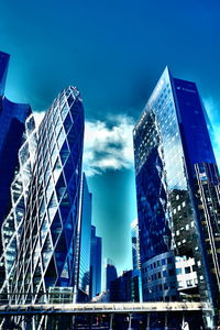 Low angle view of skyscrapers against cloudy sky