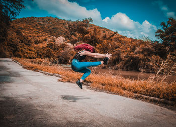 Woman on road amidst trees against sky