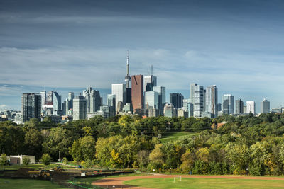 Trees and buildings in city against sky