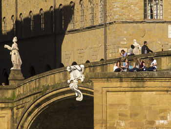 People at ponte santa trinita bridge against buildings