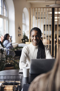 Portrait of smiling businesswoman sitting at desk in coworking office