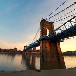 Low angle view of bridge over river during sunset