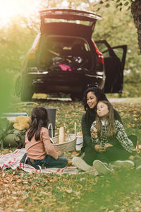 Mother and daughters enjoying picnic in autumn