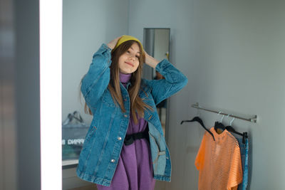 Woman wearing hat standing against wall