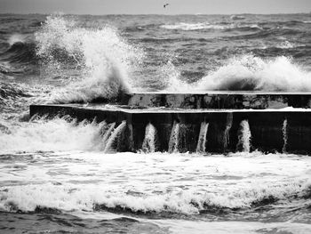 Waves splashing on shore against sky