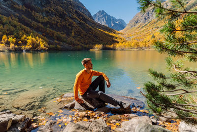 Portrait of woman sitting on rock by lake