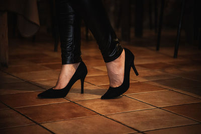 Low section of woman wearing high heels standing on tiled floor