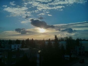 Houses and trees against sky at sunset