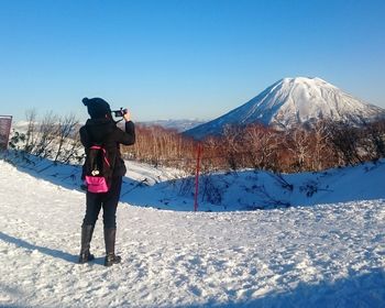 Rear view of woman photographing mt fuji against sky