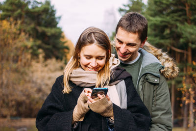 Friends looking away while standing on mobile phone