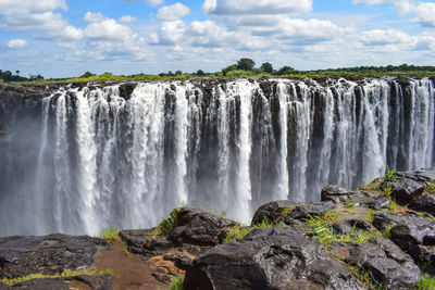 Scenic view of waterfall against sky