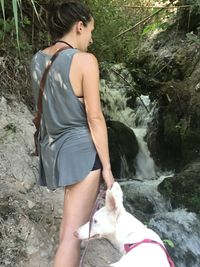 Beautiful young woman lying on rock in forest