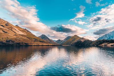 Scenic view of lake by mountains against sky