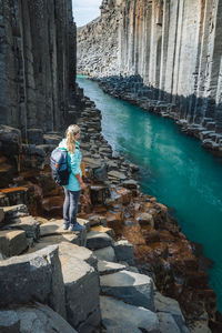 Full length of woman standing on rock by water