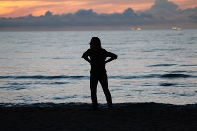 Man standing on sea shore during sunset