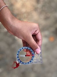 Cropped hand of woman holding navigational compass outdoors