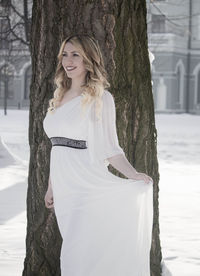 Portrait of smiling young woman standing by tree