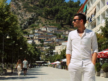 Man with hands in pockets standing on street in city