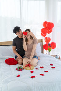 Full length of woman with red roses in bed