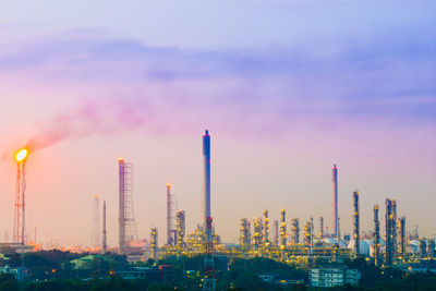 Illuminated factory against sky during sunset