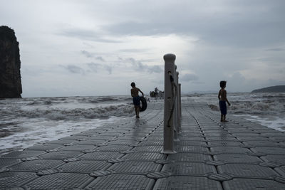 People walking by sea against sky