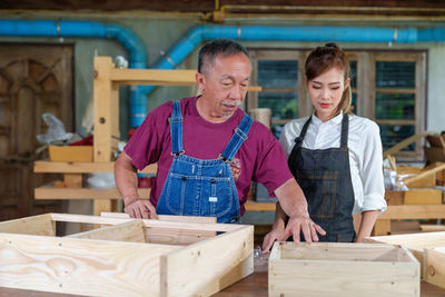 Tutor with female carpentry student in workshop studying for apprenticeship at college ,