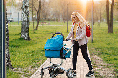 Mom in glasses walks with a stroller in the park