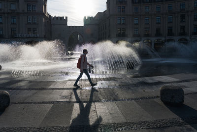 Girl walking against fountain in city