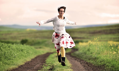 Full length of young woman running on field