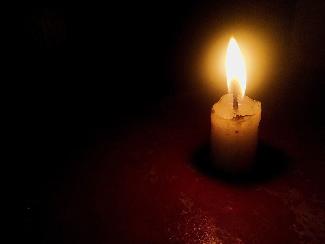 CLOSE-UP OF LIT CANDLE OVER BLACK BACKGROUND