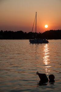 Silhouette sailboat in sea during sunset