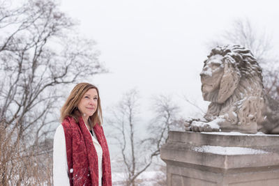 Woman standing by bare tree in winter