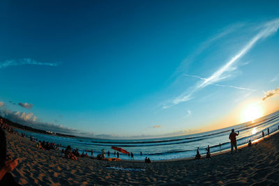 People on beach against blue sky