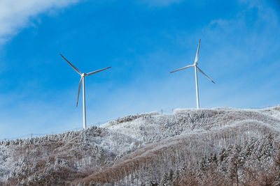 Windmill on snow covered land against sky