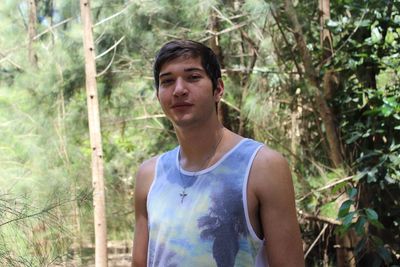 Portrait of young man standing against trees