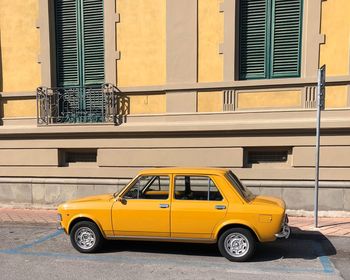 Yellow car on street against building