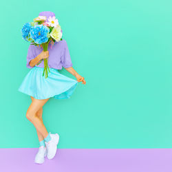 Full length of smiling woman standing against blue background