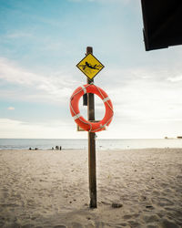 Information sign on beach against sky