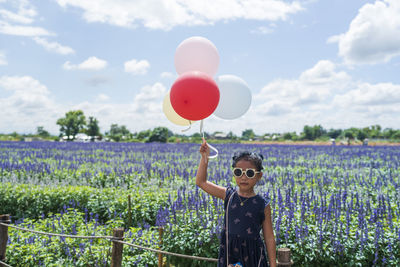 Rear view of woman with balloons against sky