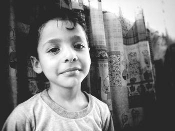 Close-up portrait of boy standing against curtain