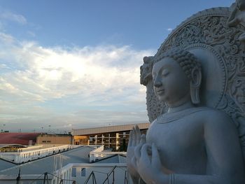 Buddha statue by building against sky