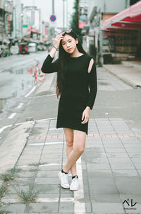 Full length of young woman standing on footpath