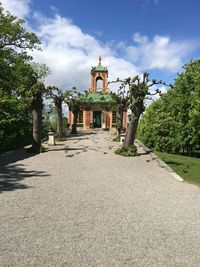 Footpath amidst trees and building against sky