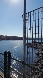 Railing by sea against clear sky