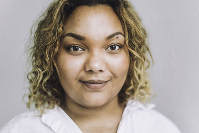 Portrait of confident fashion designer with curly hair against gray background