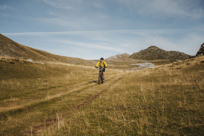 Female in warm clothing riding electric bicycle on mountain at somiedo natural park, spain