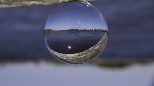 Close-up of crystal ball against sky