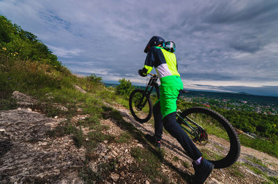 Mountain biker carries a bicycle in a forested landscape of summer mountains. mtb track for cycling