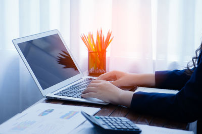 Midsection of man using laptop on table