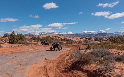 Full frame view of tourists enjoying a 4x4 tour in rugged terrain on a sunny day with mountains